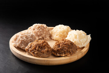 Cocada, Coconut candy from Brazil, white and brown cocadas on round wood, black background, selective focus.