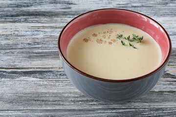 Classic Italian medieval chicken soup with herbs in a bowl on a wooden table - side view