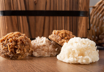 Cocada, Coconut candy from Brazil, white and brown cocadas fallen from a straw basket on wooden surface, selective focus.