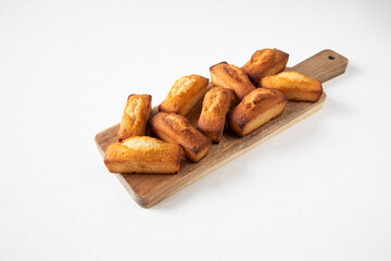 French national pastries - financier cake on a wooden board - conceptual dessert serving for a festive table or morning breakfast - side view