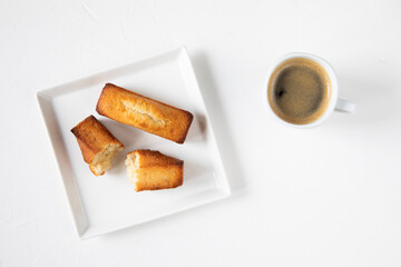 Morning black coffee with traditional French pastries - financier in white ceramic dishes on a white background - for breakfast