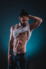 Fototapeta na wymiar Studio portrait of a beautiful masculine bearded shirtless man showing his abdomen muscles