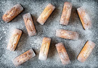 Christmas French pastries on a black background - financier cake sprinkled with powdered sugar on top - holiday concept, top view