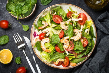 Shrimp salad with green leaves at stone table.