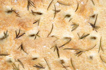 Italian focaccia - rustic local baked from flour, olive oil, yeast, sugar, salt and water, lying on an iron baking sheet like a background - top view