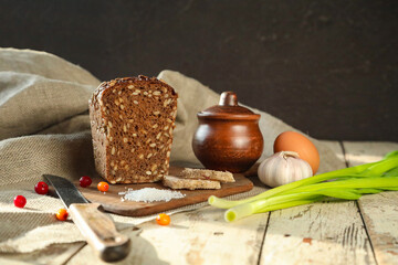 Traditional Russian breakfast in the village - black bread with white salt, chicken egg, garlic on a wooden table with a knife, buckthorn, bacon and green onions covered with burlap - copy space