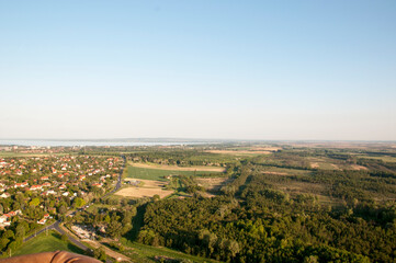 Panoramic view from a hot air balloon to town houses, forest and lake on the horizon.