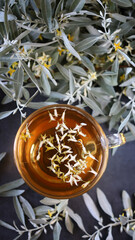 A cup of tea with sea buckthorn leaves. Flowers and branches of sea buckthorn. Tea with fresh sea buckthorn.