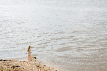 The lonely figure of a young woman at the end of the earth. The blonde is standing on a small piece of sushi. Everything around is flooded with water. High quality photo