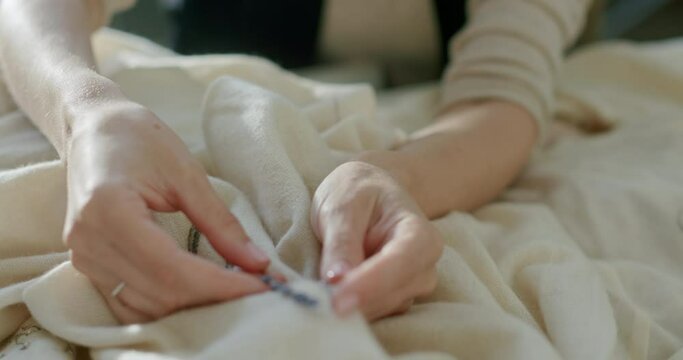 Anonymous dressmaker comparing flower with embroidery on table