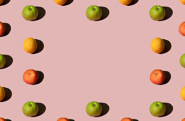 Colorful summer fruit pattern made of fresh organic green apples, lemons and mandarin oranges on pink pastel background. Contramporary minimal geometric concept.