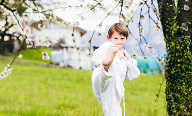 The child trains by doing karate in the open air.