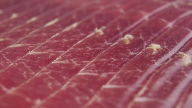 Jamon is stacked in rows. Cured traditional cooked meat. Macro. Dolly Shot