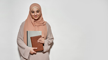 Happy young arabian girl student in hijab with notepad