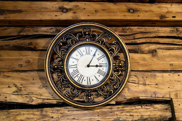 Fototapeta na wymiar A round copper clock of the nineteenth century hangs on the wooden wall of old house