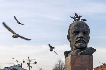 Pigeons sit on the monument to Lenin's head in the central square of the provincial city