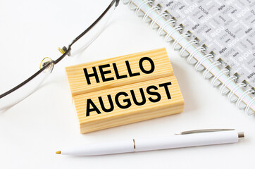 Text Hello August on a wooden blocks lying near notepad with eyeglasses and pen