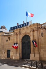 Portail d'entrée de l'hôtel de Matignon, palais de résidence officielle du Premier Ministre français, rue de Varenne à Paris, surmonté d'un drapeau français (France) - obrazy, fototapety, plakaty