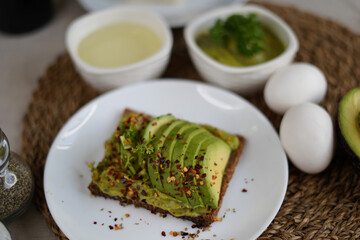 Green fresh organic avocado with black bread and spices in a plate with avocado oil and pine nuts