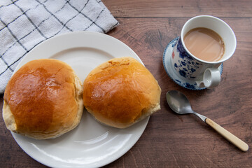 Baked char sui bao or BBQ pork buns on a table served with milk tea