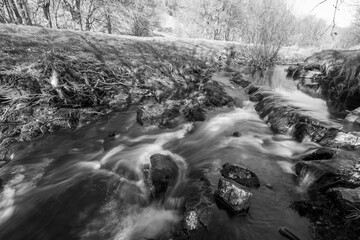 Obraz premium Long exposure of the Weir Water river flowing through the valley at Robbers Bridge in Exmoor National Park