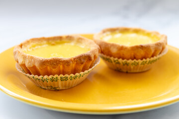Closeup of two egg tarts on a yellow plate