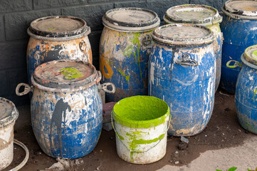 Industrial Waste, Plastic barrels of paint. High Angle View Of Liquids In Containers Against Wall. Dirty containers with stains of dye. Barrel covered with multicolored spots