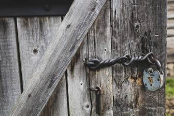 Vintage rusty padlock on old wooden door of abandoned house. Retro locks closeup. Village composition. Iron details. Soft focus