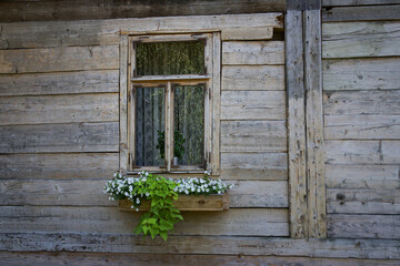 The window of an old wooden house, decorated with flowers.