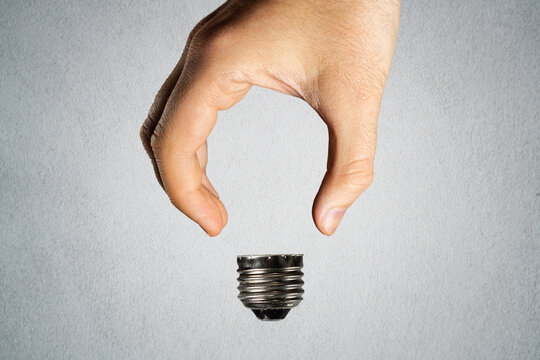 Man holding invisible bulb and visible socket on light background. Negative space