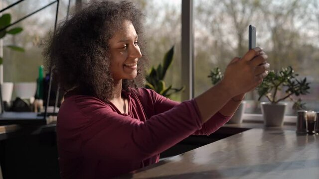 Afro American Woman With Beautiful Curls Taking a Selfie In a Cafee
