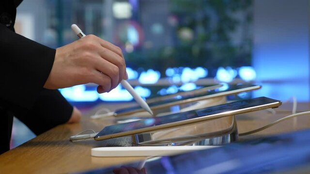 Customer woman using pen device, try new tablet at store showroom, close up shot. Thin modern portable computers set out for test by visitors.