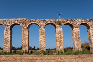 Fototapeta premium The 200 year old Ottoman aqueduct, supplied water from Cabri springs to Acco, western Galilee, Israel. Middle aged female posing at the upper line of the aqueduct.