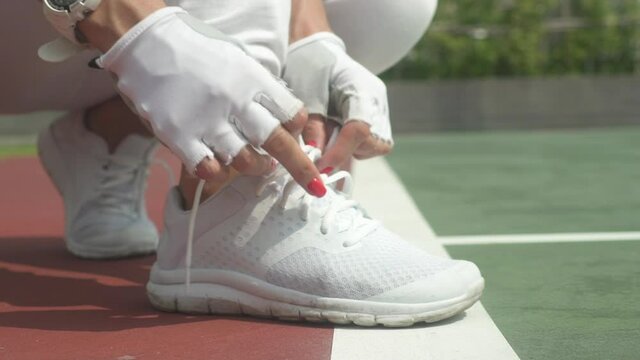 Manicured Nails Tying Shoelaces of White Tennis Shoes