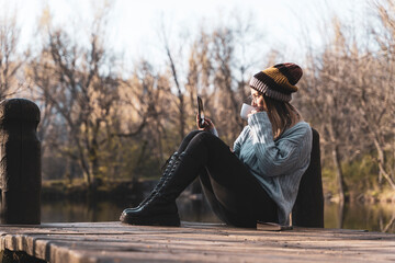 women relaxing in the wooden pier lake with smartphone.