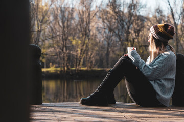 women relaxing in the wooden pier of lake with a cup of coffe.