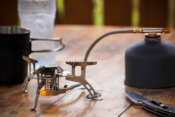 a tourist gas burner and a gas cylinder stands on the table, next to a mug, a bottle of water and a knife