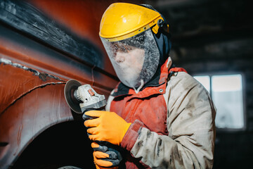 male factory worker grinds metal welds with a grinder.