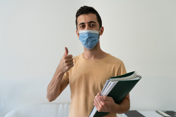 Student standing looking at camera and making an approving gesture. Concept of studying with safety.