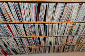 A bookshelf filled with multiple rows of record albums in their covers. The retro collection of...