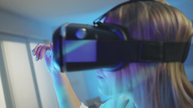 Close up of a Caucasian woman with VR glasses watching a virtual simulation of a concert and light show, dancing and swinging in the rhythm of the music