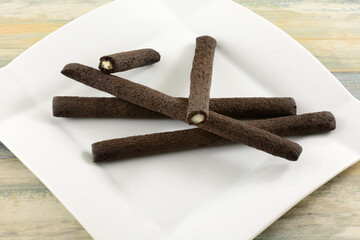 Chocolate cereal sticks filled with sweet milk cream on white snack plate
