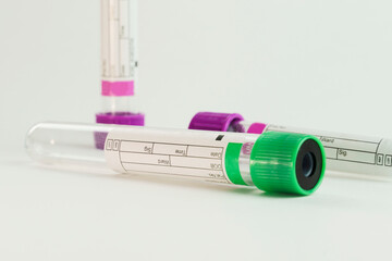 vacuum tubes for collection and blood samples on white background..Transparent with purple and green lid. Label to identify the data. Selective focus.