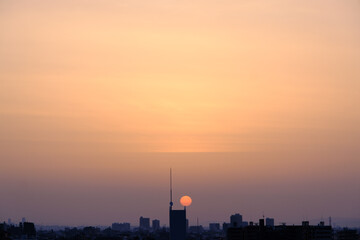 神戸市東灘区の高層マンションからの日の出、東の空がオレンジ色に染まり、神戸・芦屋・西宮の街並みがシルエットで浮かぶ。一日の始まり