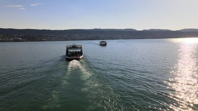 Aerial drone shot following two car ferries sailing towards each other on Lake Z&uuml;rich in Switzerland