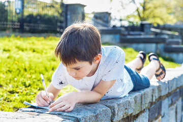 boy writing something outside 