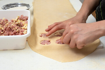 hands filling homemade pasta in sorrentino mold with ham and cheese and pumpkin filling on worktop with flour bowls and rolling pin and plastic molds