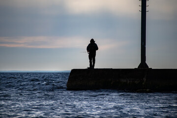 Silhouette of a man fishing off of a pier on Lake Michigan