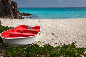 Fototapeta na wymiar Small red rowboat on the sand on the Caribbean island of St Bart's
