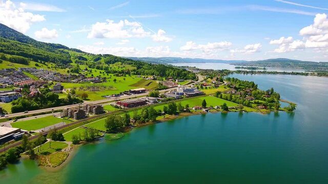 Aerial view of beautiful natural landscape of Altendorf, Switzerland, with sea water, roads, vehicles, houses, and mountains